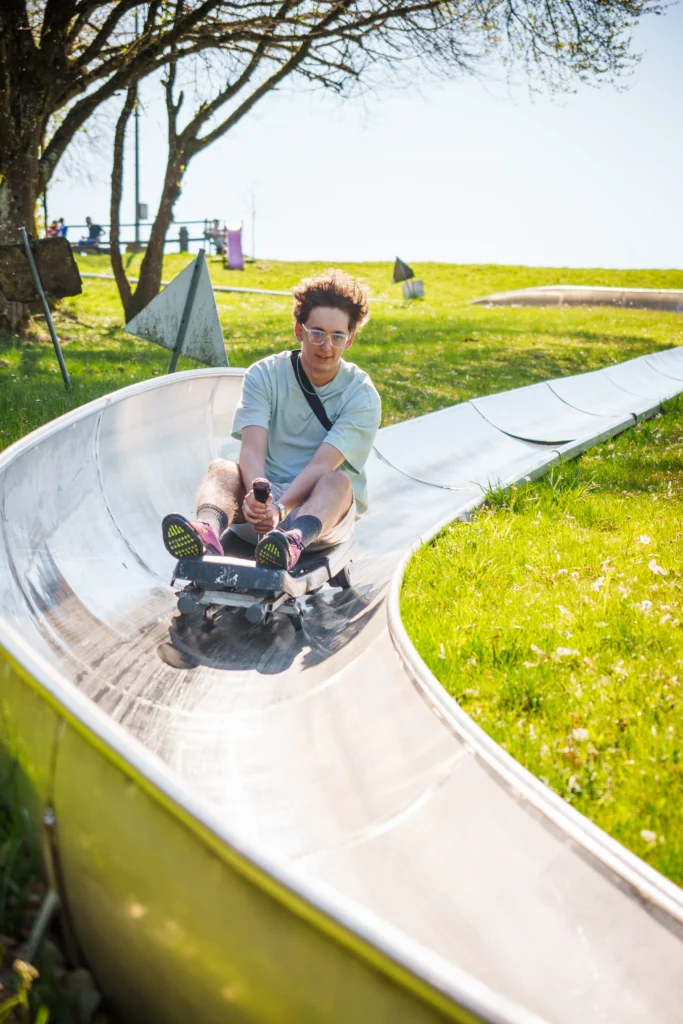 Junger Besucher fährt auf der Sommerrodelbahn im Rodelzentrum Kaisersbach durch eine Kurve.