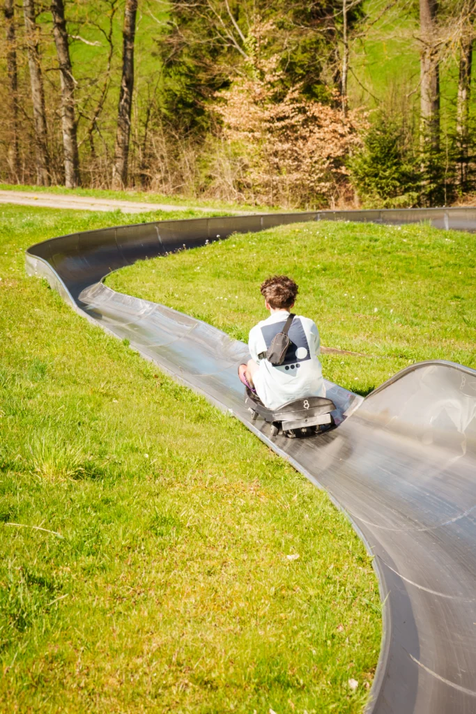 Junger Besucher fährt auf der Sommerrodelbahn im Rodelzentrum Kaisersbach durch eine langgezogene Kurve.