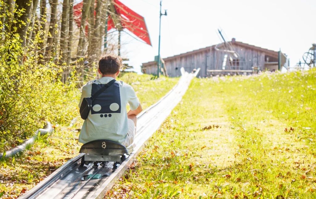 Kind fährt auf der Sommerrodelbahn im Rodelzentrum Kaisersbach den Hang hinauf.