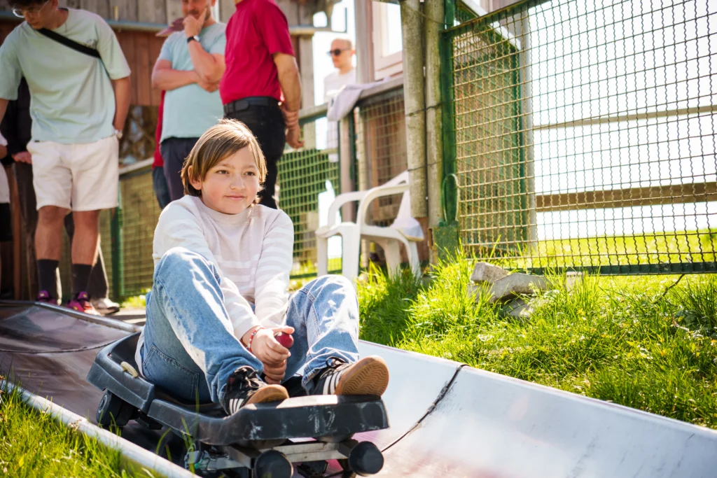 Kind sitzt auf der Sommerrodelbahn im Rodelzentrum Kaisersbach am Startbereich.