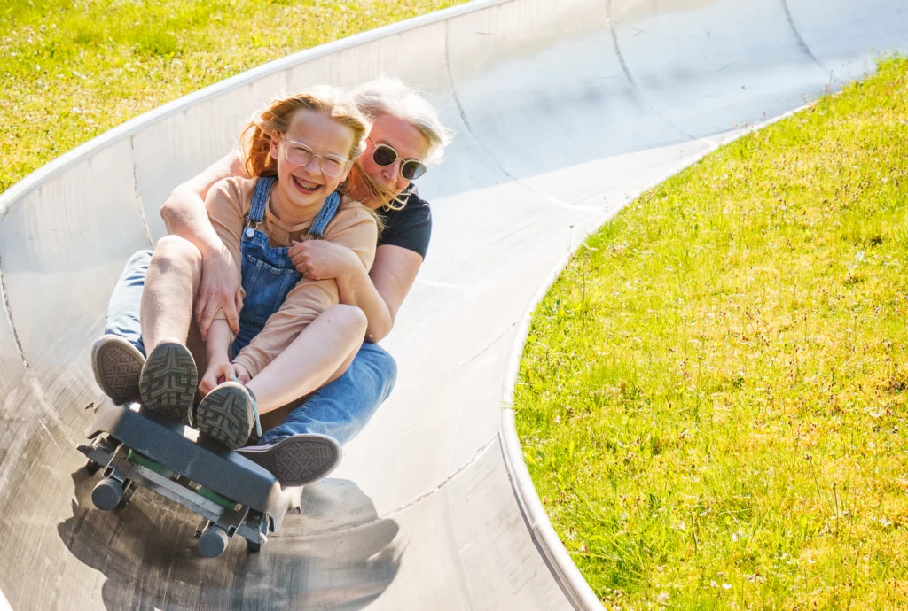 Zwei Personen fahren gemeinsam auf der Sommerrodelbahn im Rodelzentrum Kaisersbach.